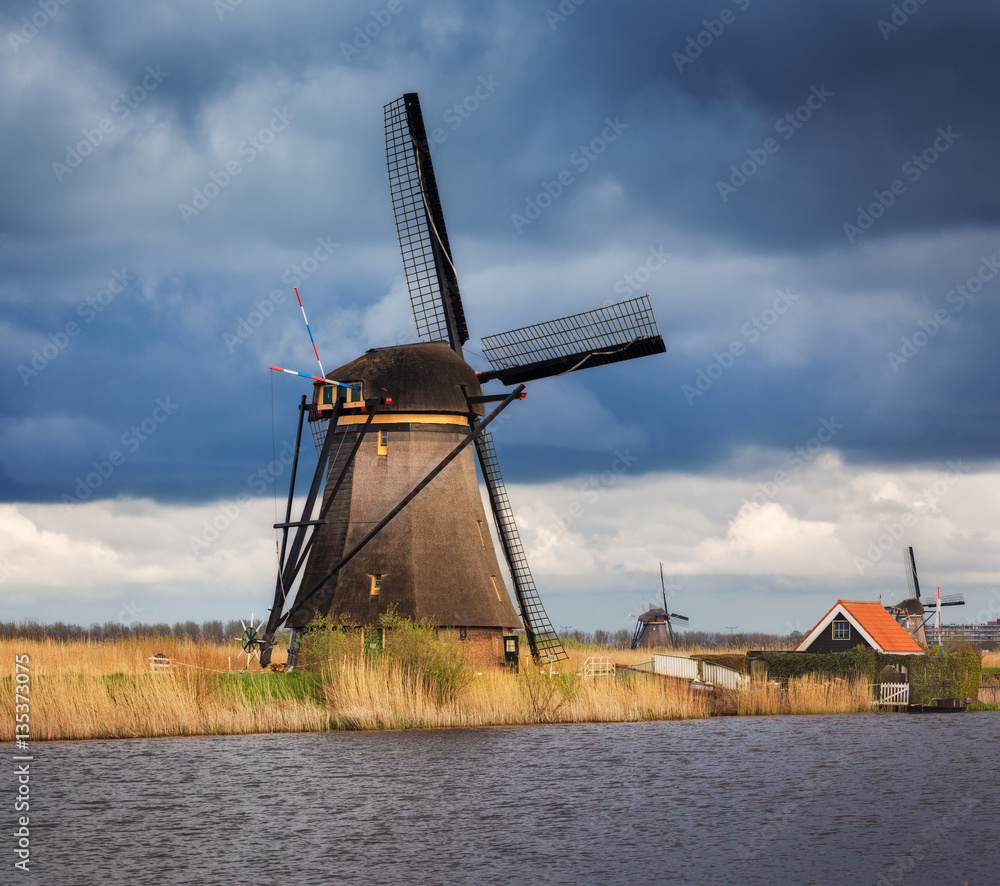 Windmills against cloudy sky at sunset in famous Kinderdijk, Netherlands. Rustic landscape with trad