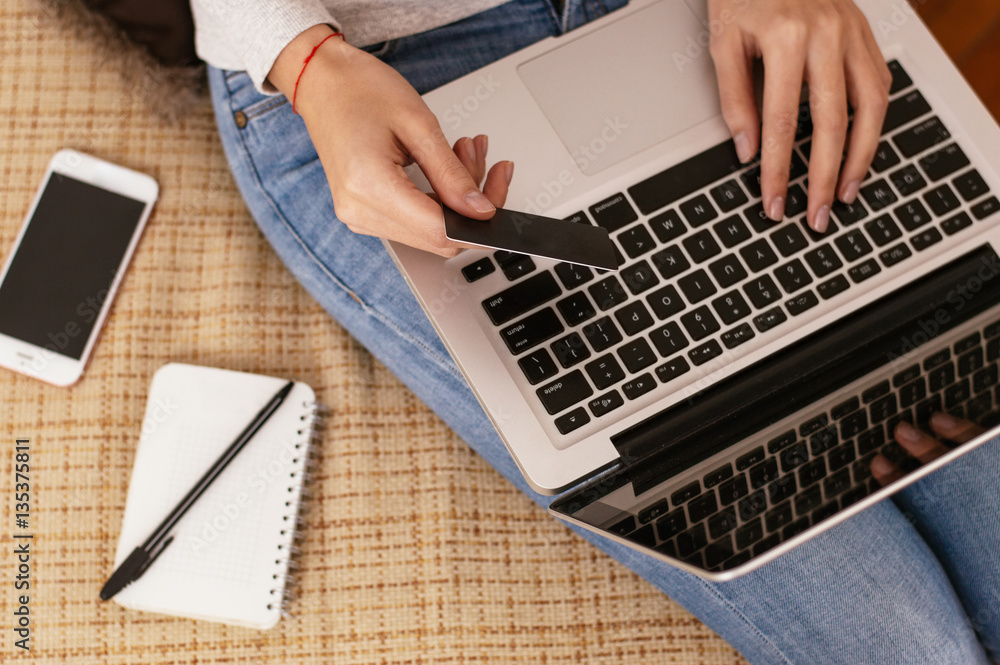 Woman working with laptop and holding blank bank card