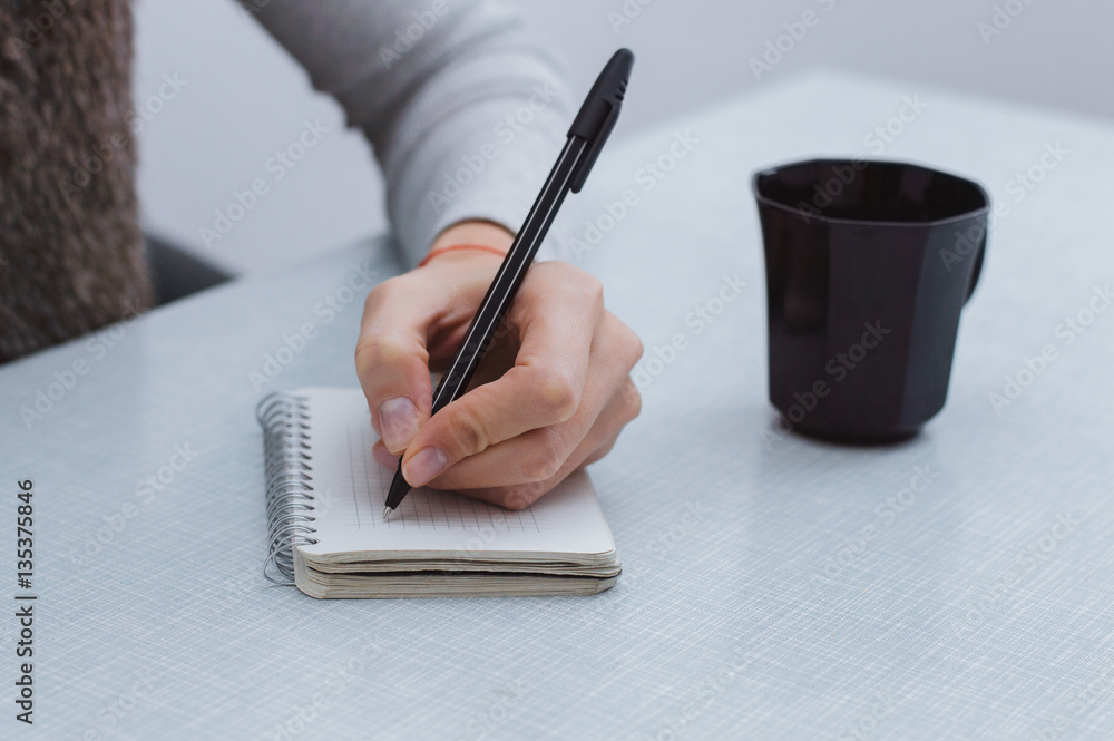 Focus on woman hands writing in notes.