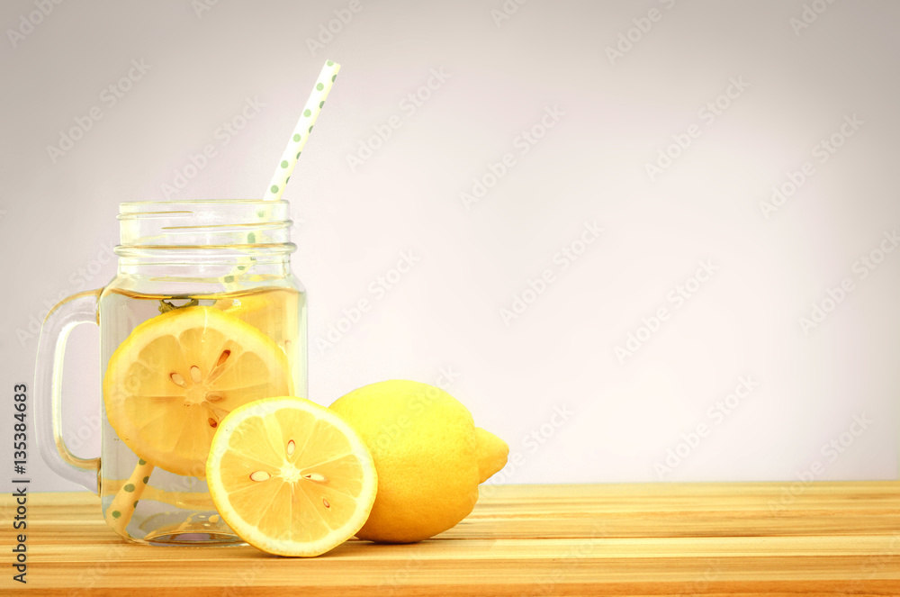  Citrus lemonade water with lemon sliced , healthy and detox water drink in summer on wooden table .