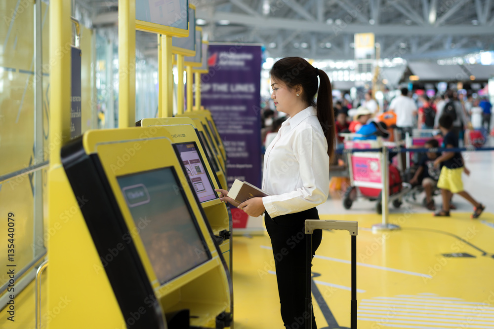 Young Asian businesswoman using self check-in kiosks in airport.