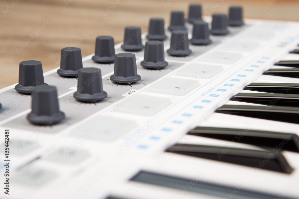 Close up of MIDI controller volume fader, knob and keys.