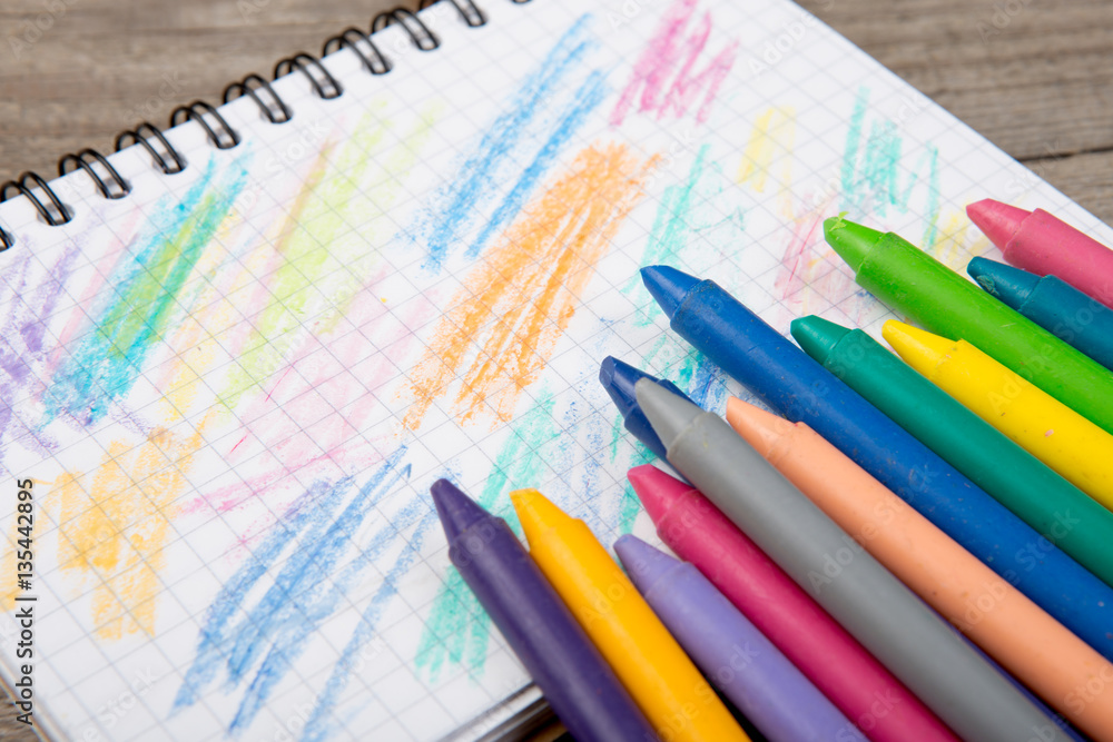 colored crayons and blank page on the wooden table