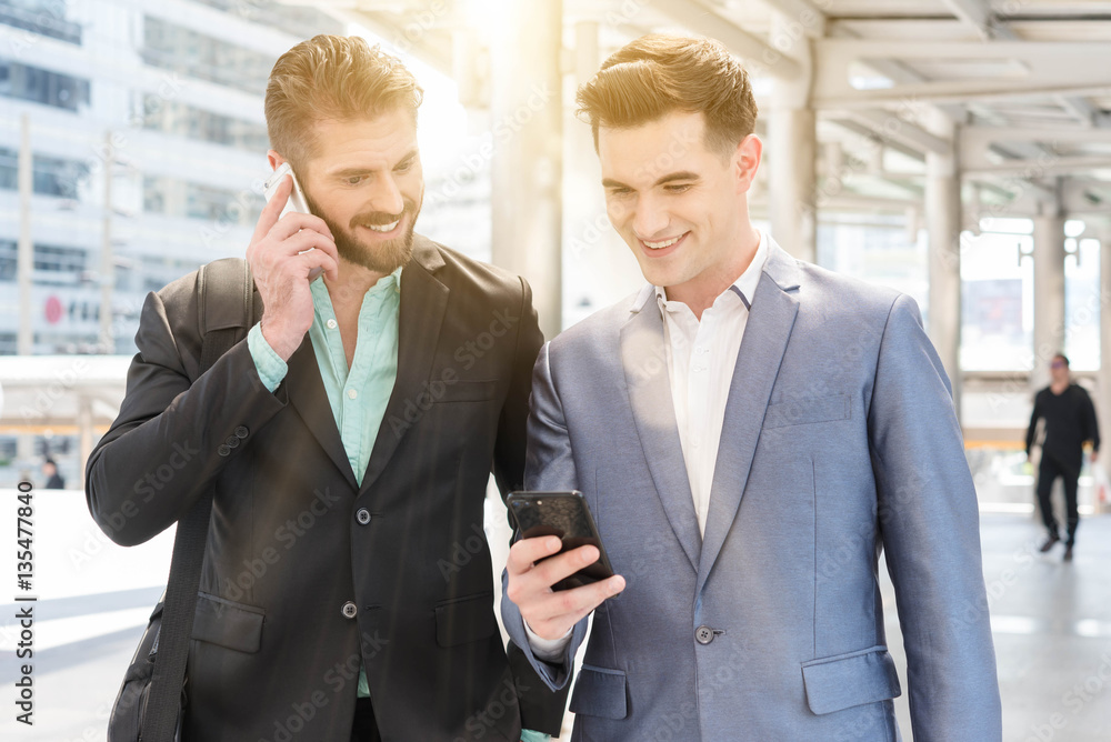 Two Westerner Business men talk and use smart phone