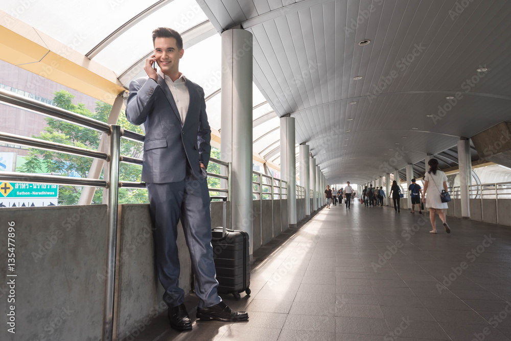 Business man with travel bag use smart phone on the walk way wit