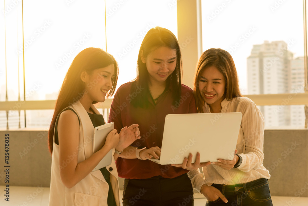 Three woman use laptop together in afternoon sun