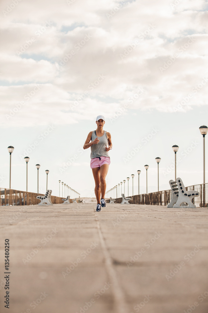 Young woman running on the sea side promenade