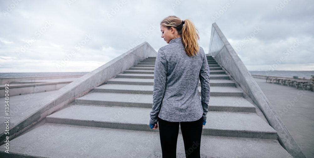 Fitness female standing by steps in morning