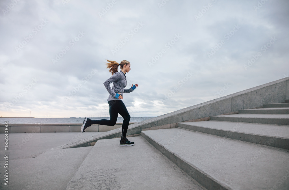 Fitness woman running up on steps