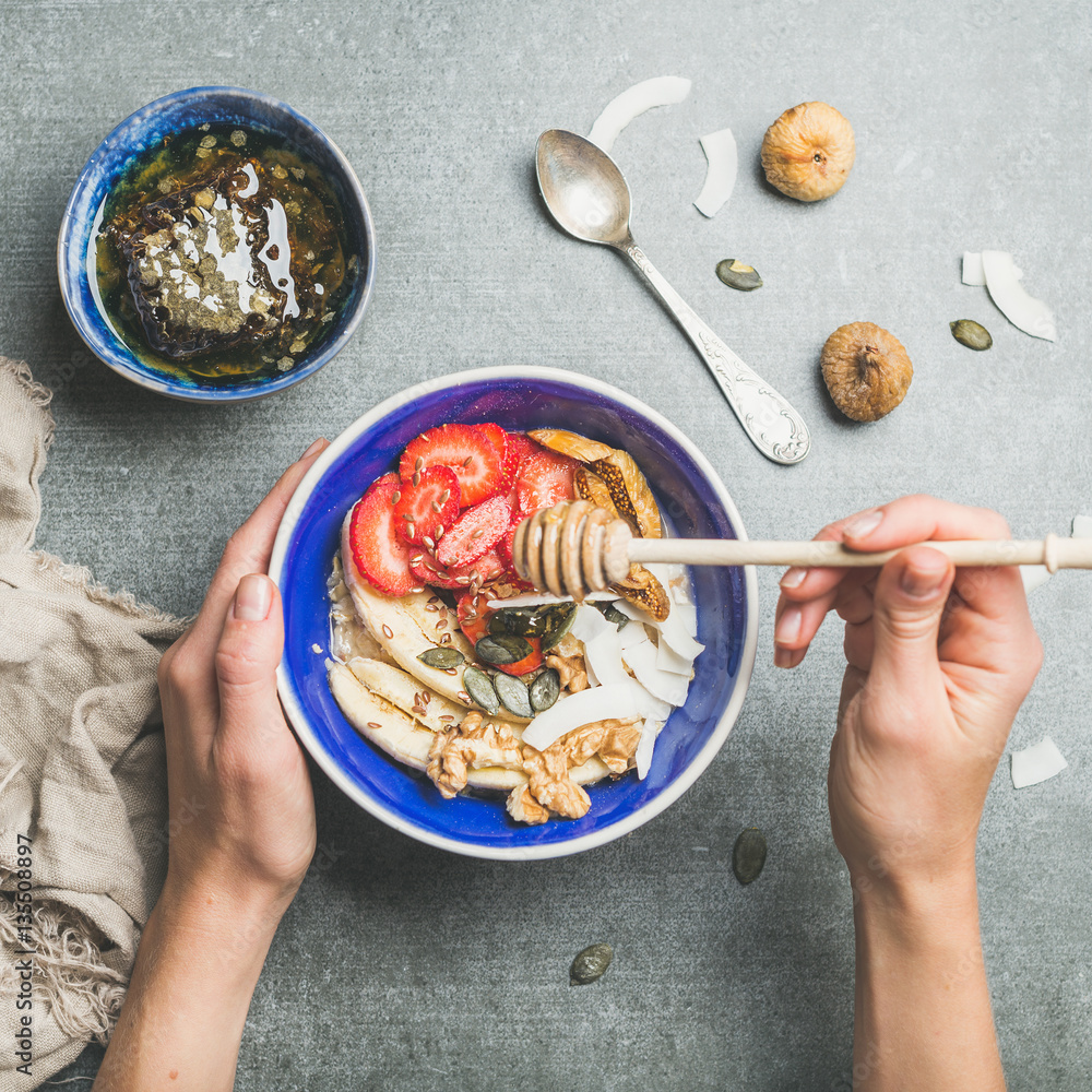 Healthy breakfast bowl. Yogurt, granola, seeds, fresh and dry fruits and honey in blue ceramic bowl 