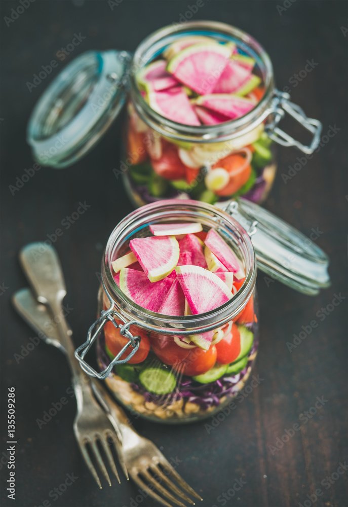 Healthy take-away lunch jars. Vegetable and chickpea sprout vegan salad in glass jars over dark scor