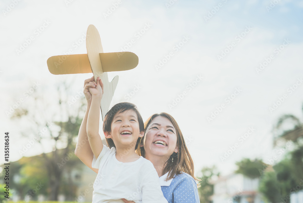 Asian mother and son playing cardboard airplane together