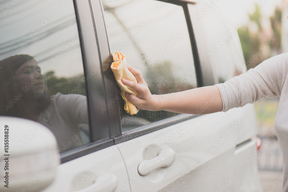 woman washing car window with microfiber cloth