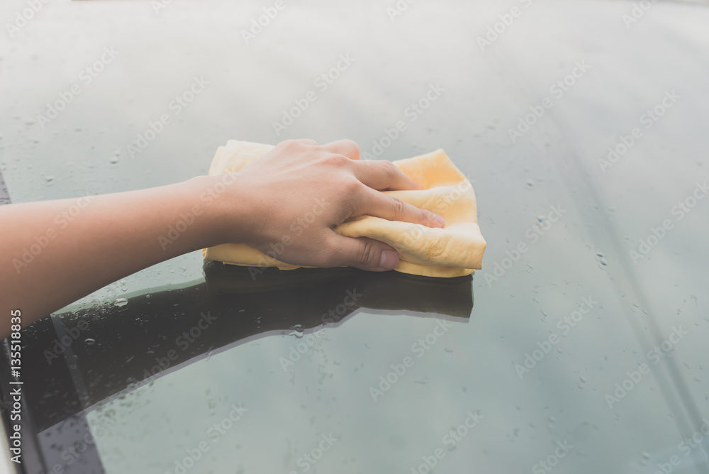 woman washing car window with microfiber cloth