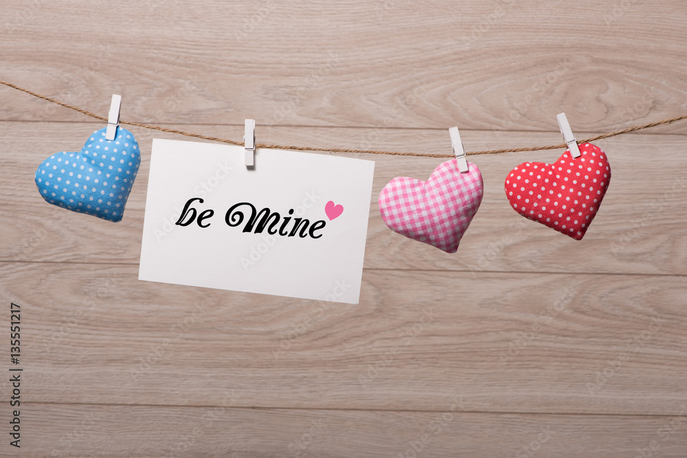 Textured hearts hanging on blue wooden background with blank pap