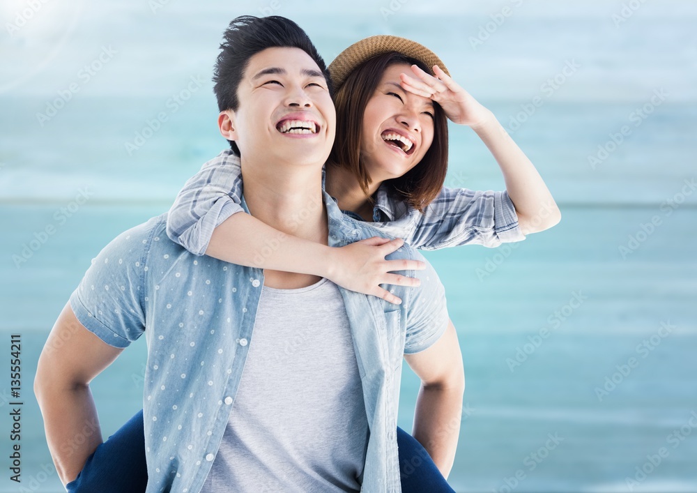 Happy man giving woman piggyback on beach