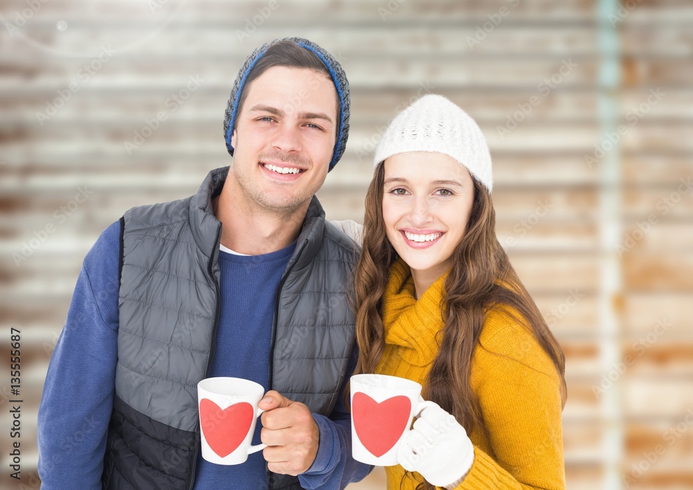 Happy couple holding mugs with heart shapes on them