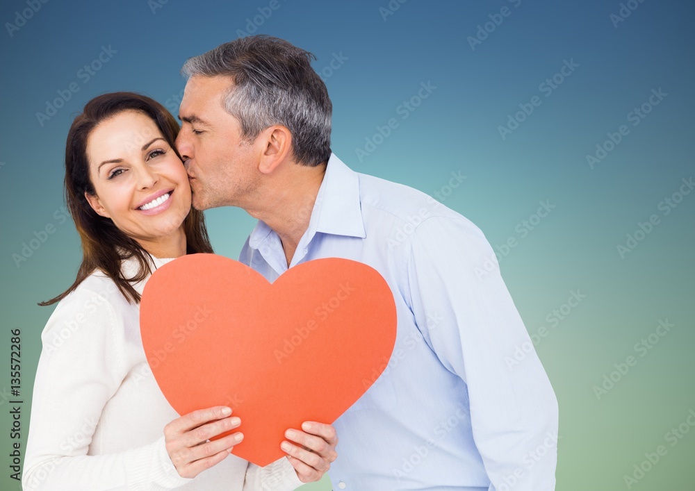 Mature man kissing woman holding a heart