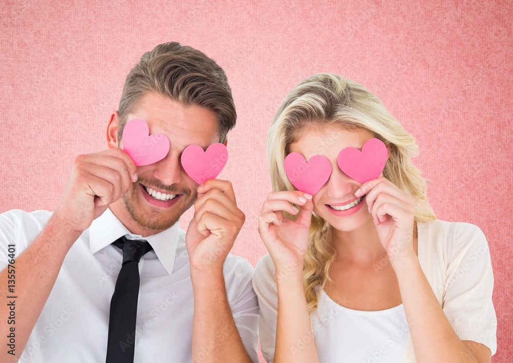 Couple holding hearts over eyes