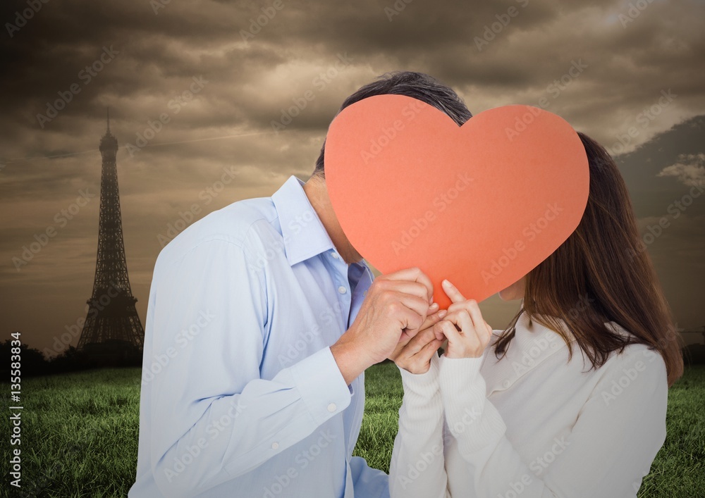 Romantic couple hiding their face behind heart