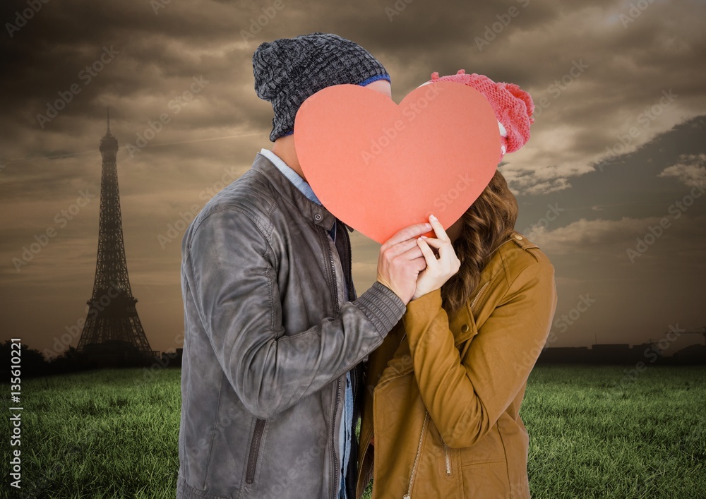 Romantic couple hiding their face behind heart