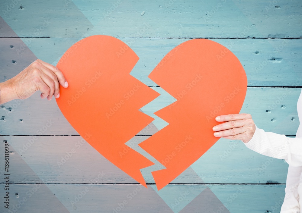 Couple hands holding broken heart against wooden background