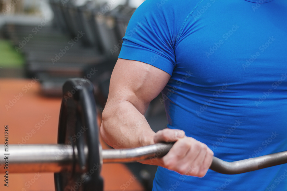 Closeup of a muscular young man lifting weights