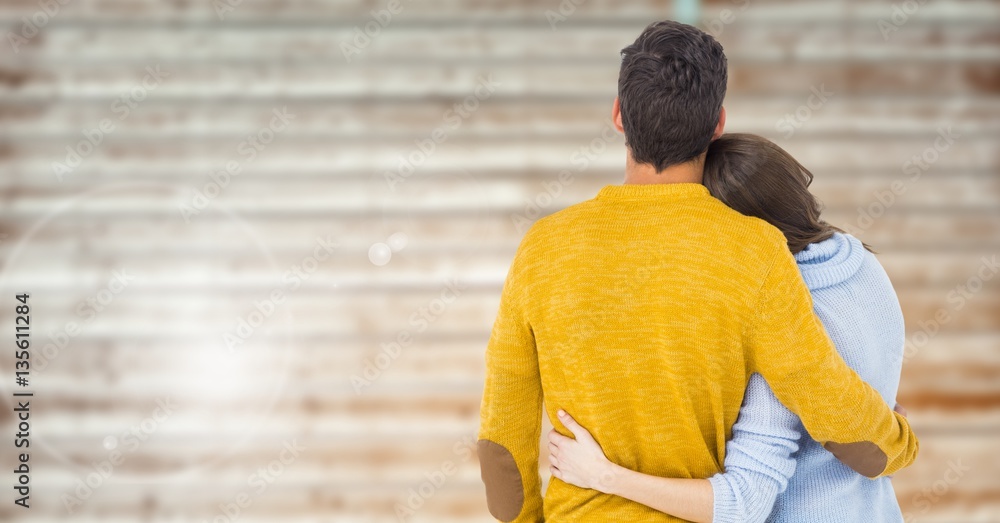 Rear view of couple embracing against wooden background