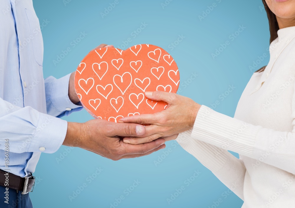 Couple holding pink heart shape box against blue background