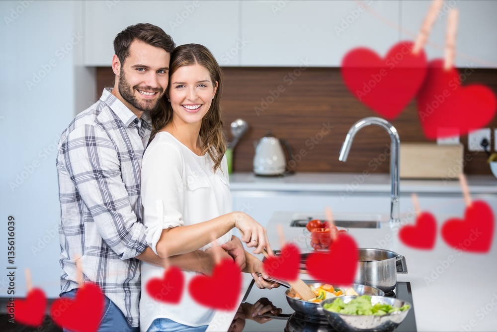 Composite image of hanging red heart and couple cooking food