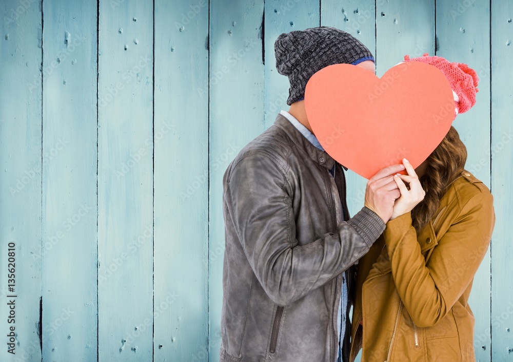 Couple hiding their face behind red heart