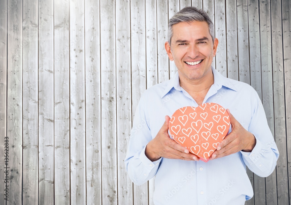 Portrait of happy man holding heart shape gift box