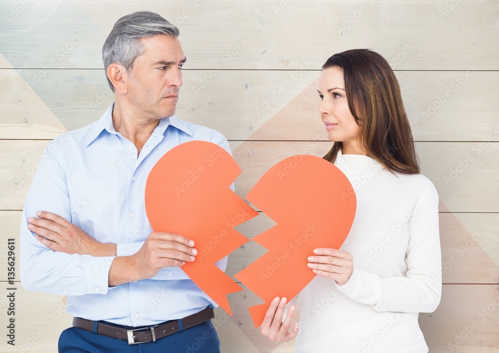 Sad couple looking each other while holding broken hearts