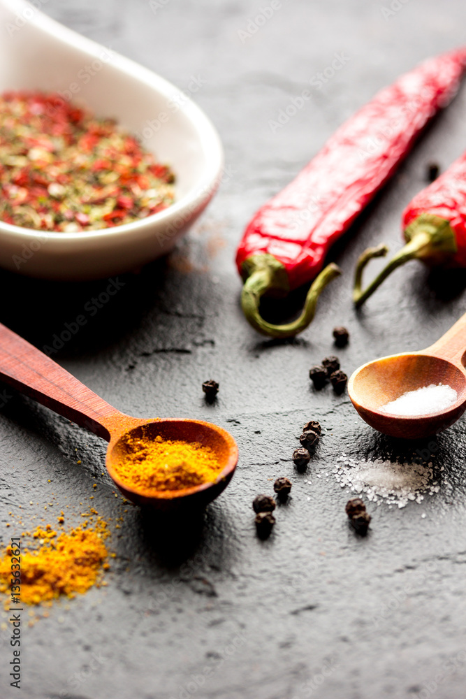 spices in wooden spoon on dark background