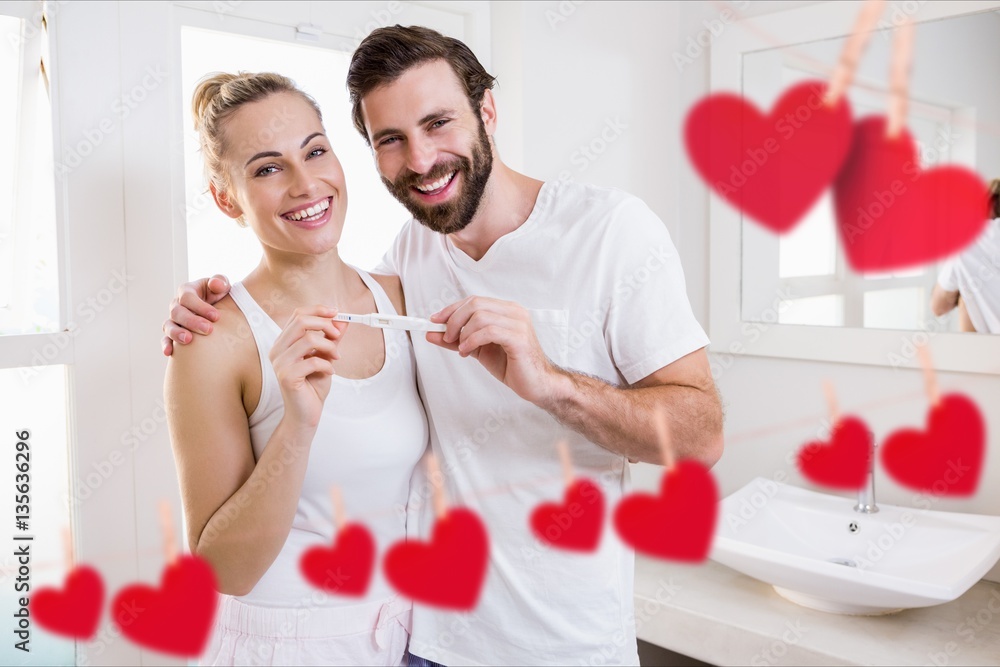 Portrait of happy couple holding pregnancy test in bathroom