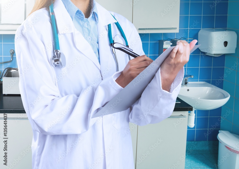 Mid section of female doctor writing on clipboard