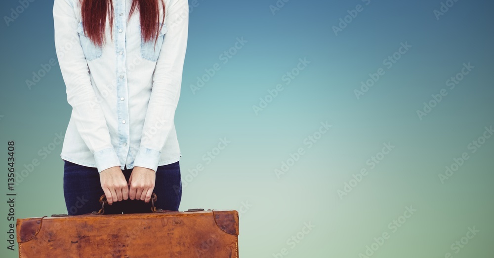 Mid section of woman holding heavy suitcase