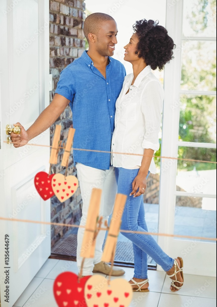 Couple embracing at home with hanging hearts around