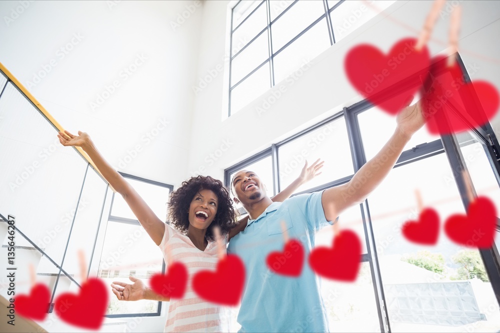 Couple embracing at home with hanging hearts around