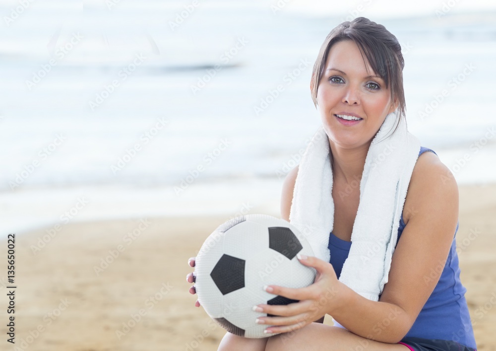 Beautiful woman holding football on the beach