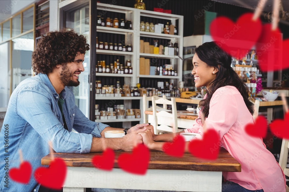 Composite image of romantic couple holding hands in a restaurant