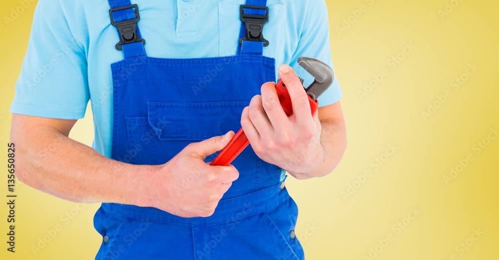 Mid section of handyman holding pipe wrench