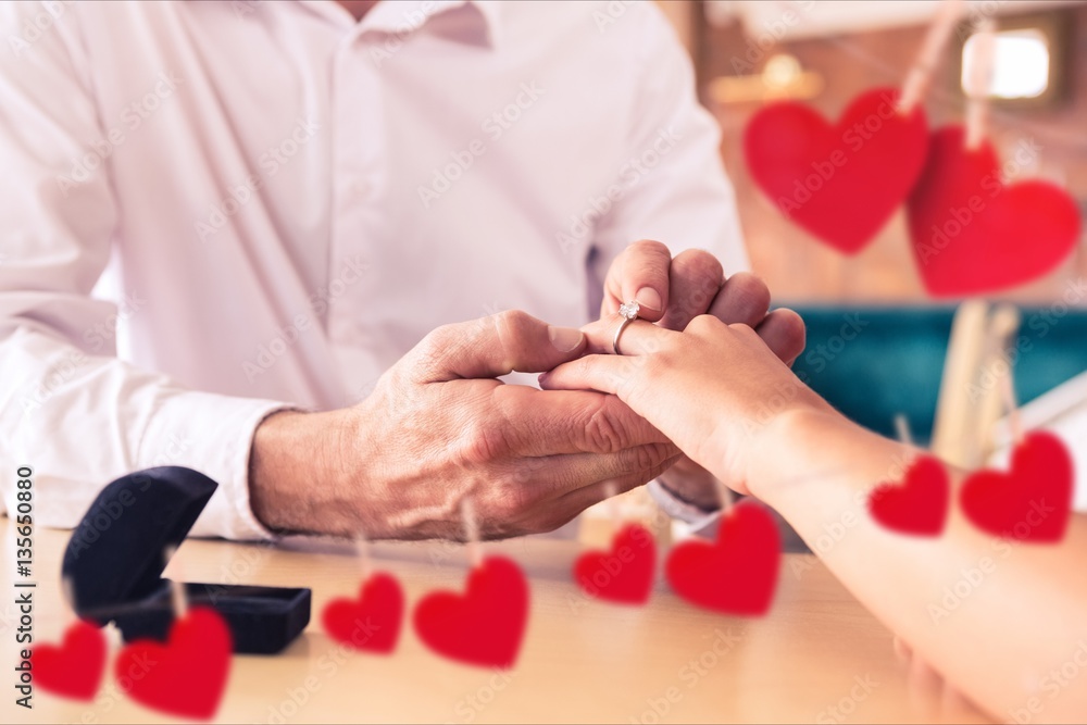 Composite image of romantic couple exchanging rings