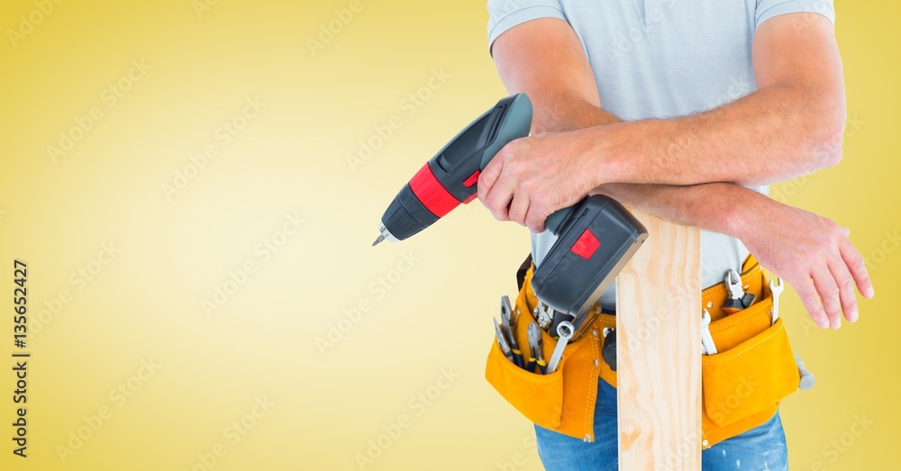 Mid section of handyman holding drill machine and plank