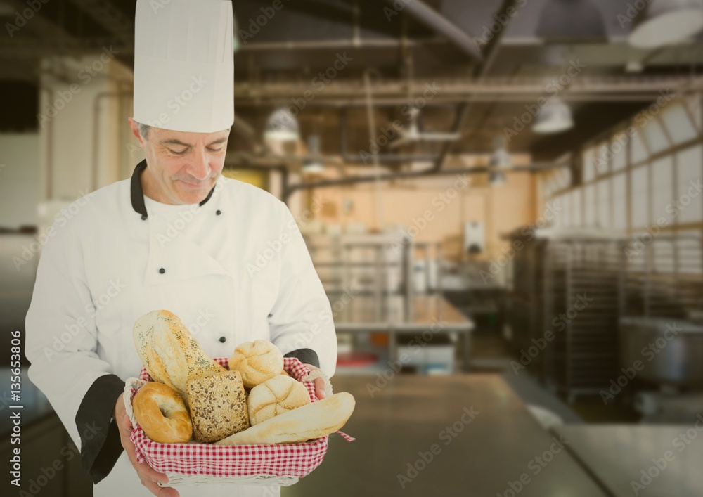 Male chef holding various bread loafs in bakery