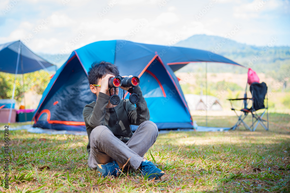 Young asian boy looking through binocular in camping