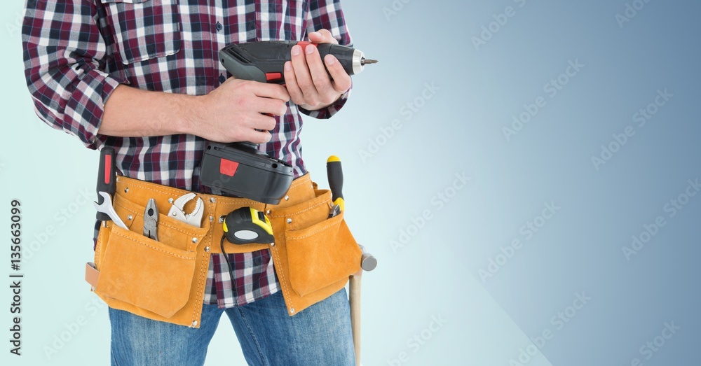 Mid section of handy man with tool belt holding a drill