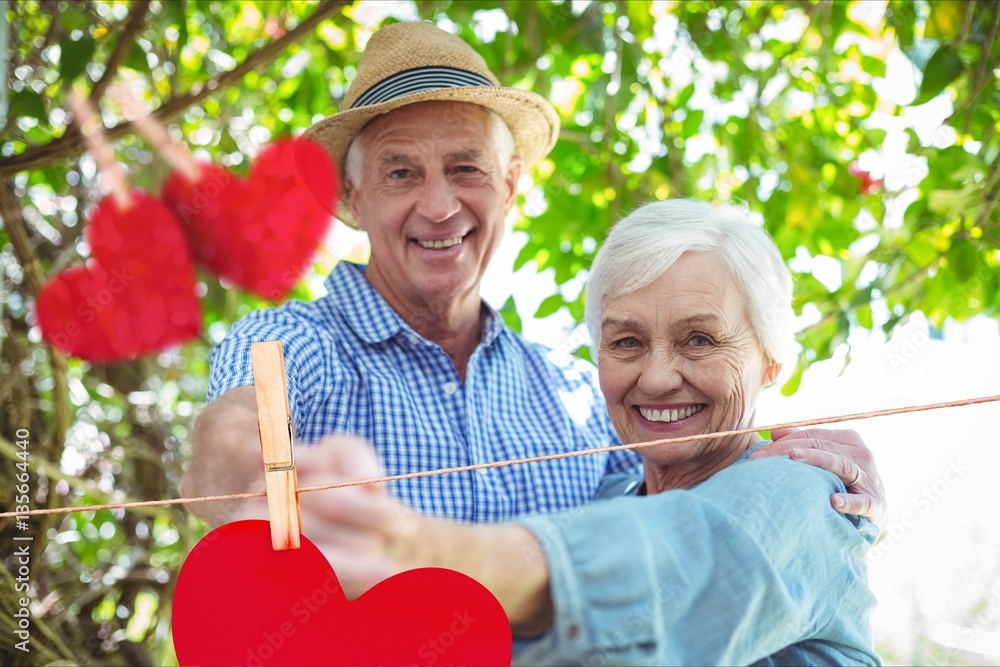 Composite image of red hanging hearts and senior couple dancing