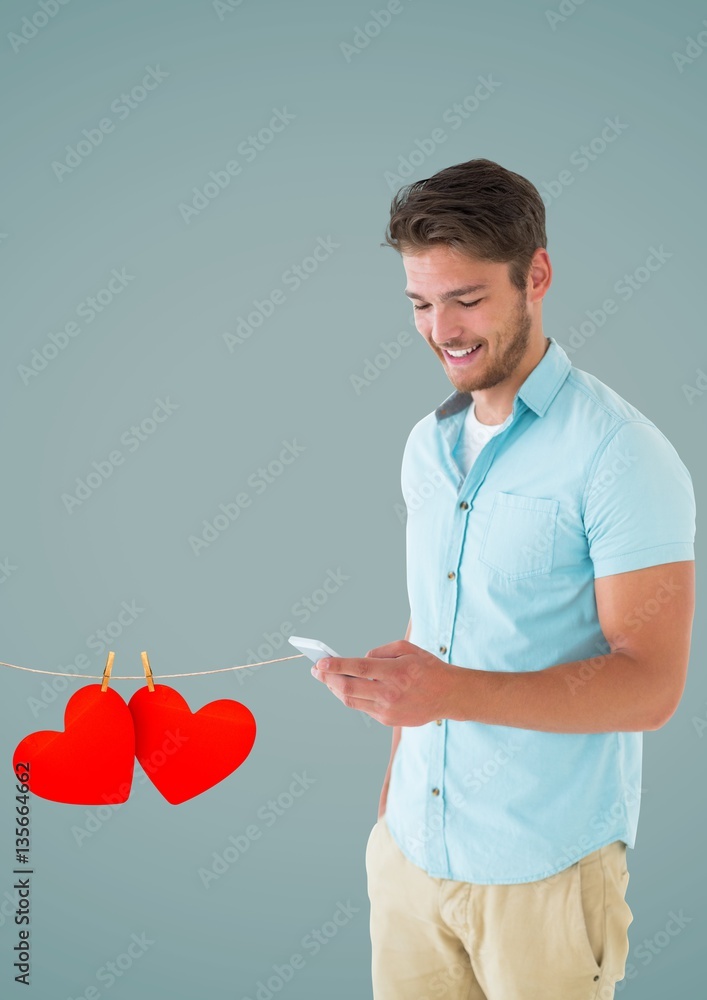 Composite image of smiling man texting and hanging red hearts 