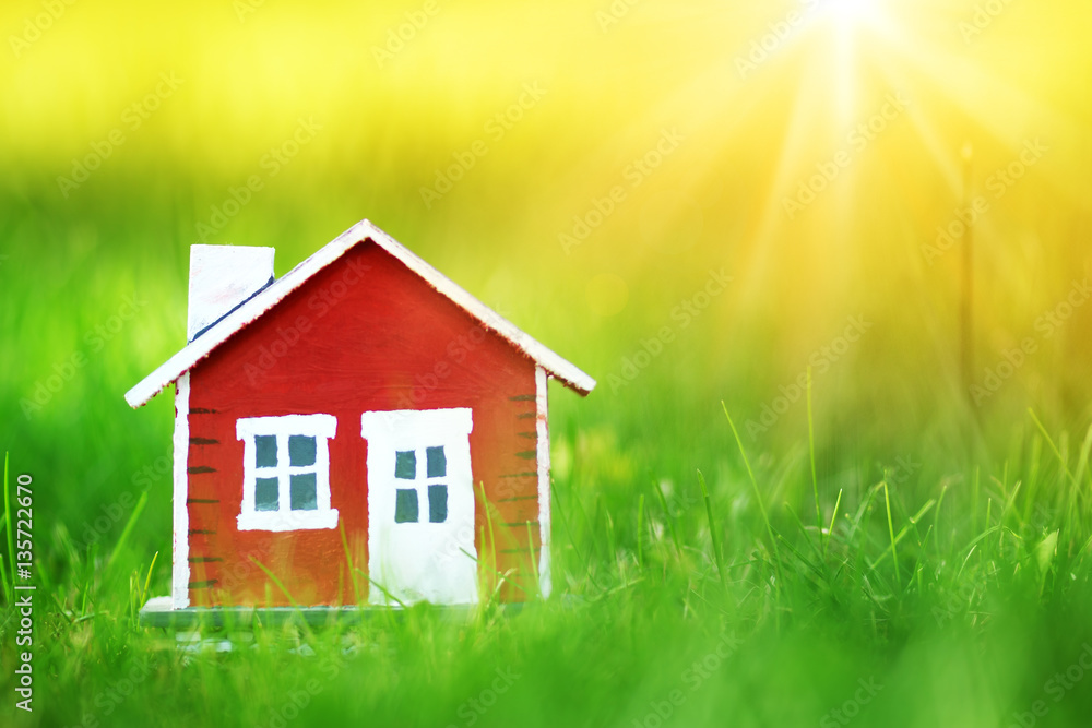 red wooden house model on the grass in garden